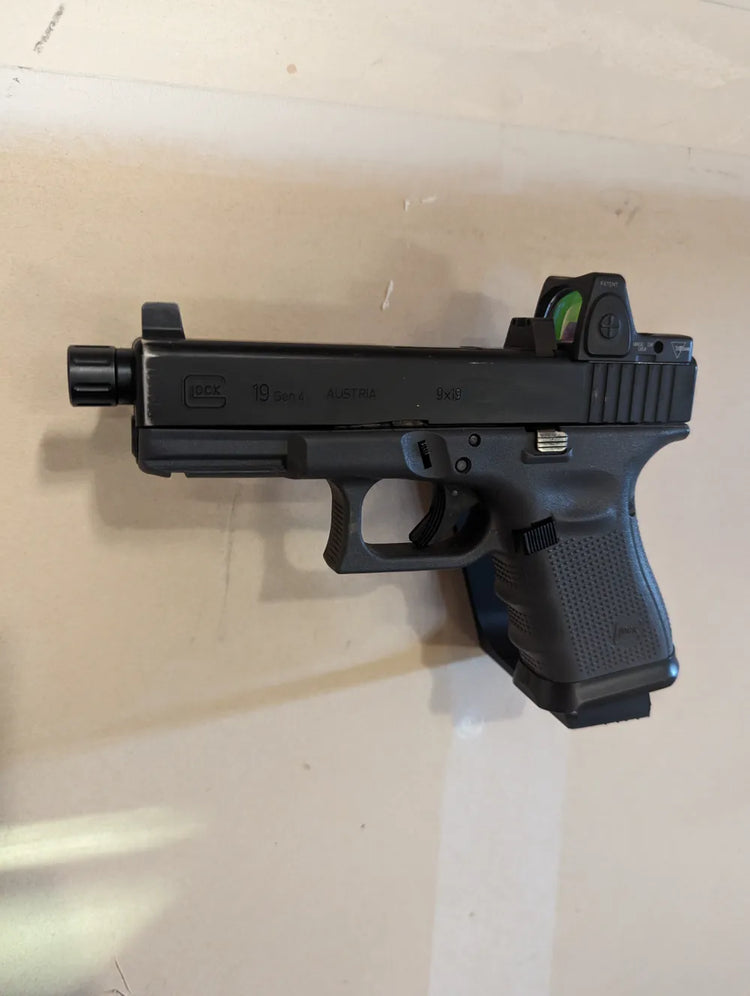 Réplica Glock de airsoft mostrada en un soporte de pared; réplica y accesorios no incluidos.