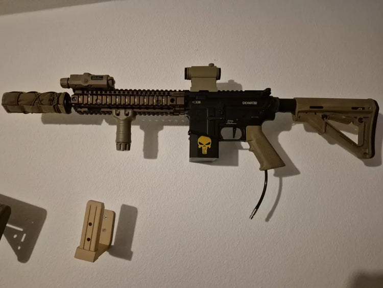 Réplica AR15 de airsoft mostrada en un soporte de pared; réplica y accesorios no incluidos.