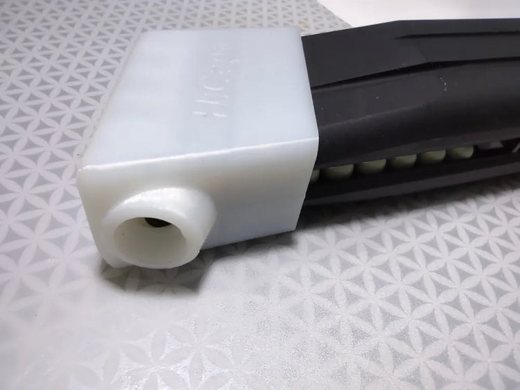 Accesorio blanco de carga y protección de pulgar mostrado sobre un cargador HiCapa GBB de airsoft.