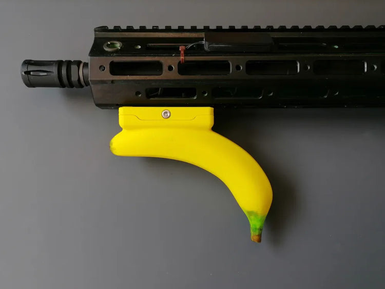 Empuñadura amarilla en forma de banana tipo Picatinny, mostrada en un equipo de airsoft no incluido.