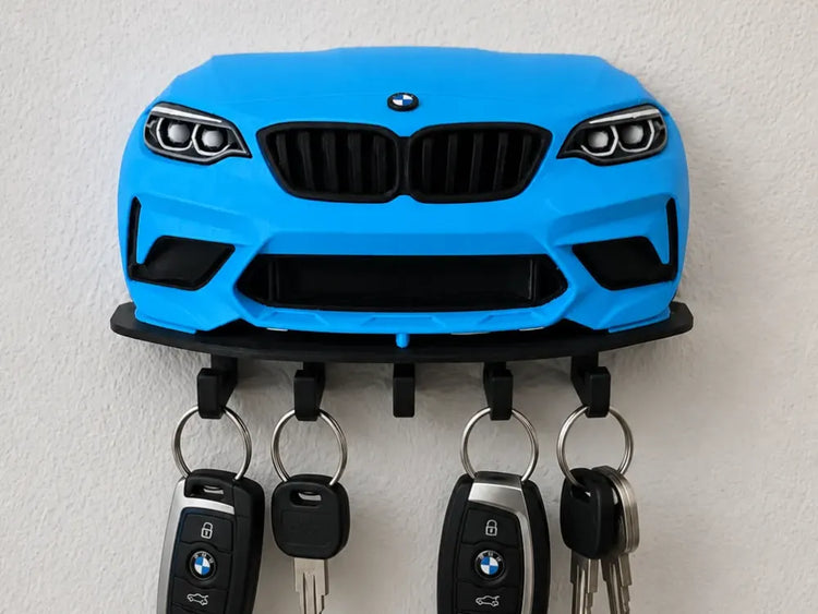 Soporte de pared para llaves con diseño de frontal BMW azul y cinco ganchos negros.