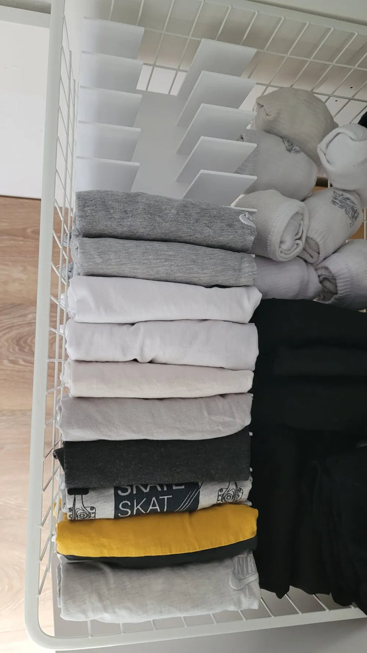 Organizador de camisetas mostrado en una cesta con prendas no incluidas.