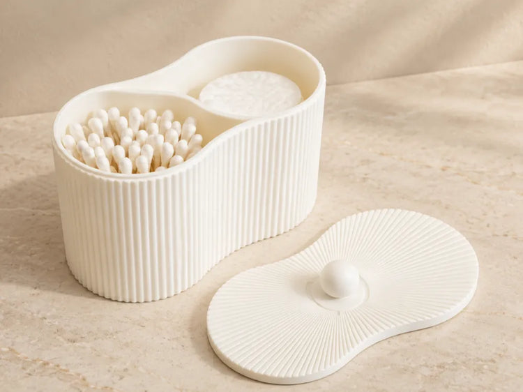 Organizador de baño con dos compartimentos, exterior acanalado y tapa, mostrado con discos de algodón y bastoncillos.